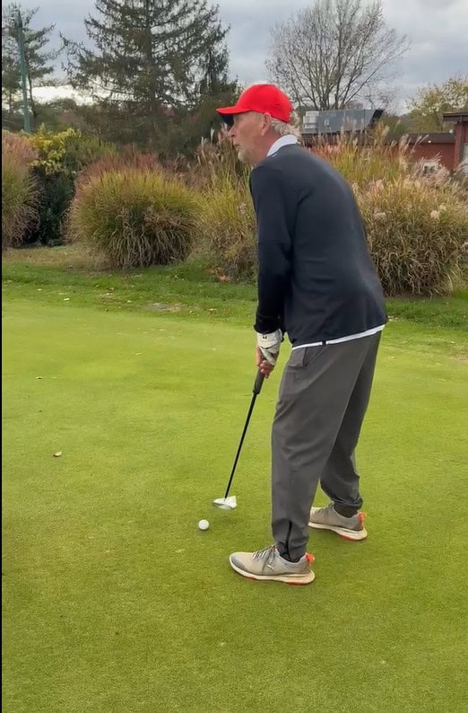 Golf putting with SAG Putter on lush green course.