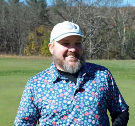 Stylish golfer wearing SAG Putters floral shirt on golf course.